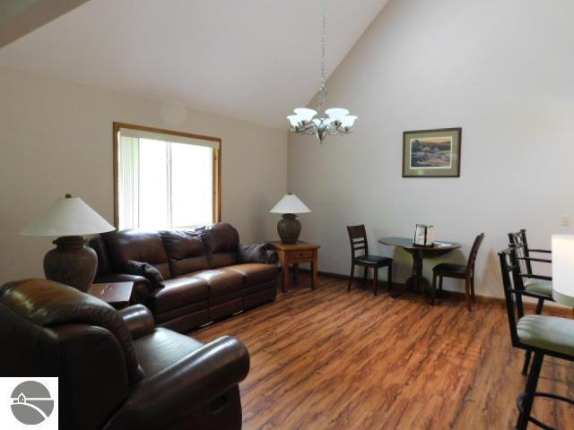 12149 Cabin Ln, Rapid City, MI 49676 - living room with a chandelier, light wood-style floors, and high vaulted ceiling