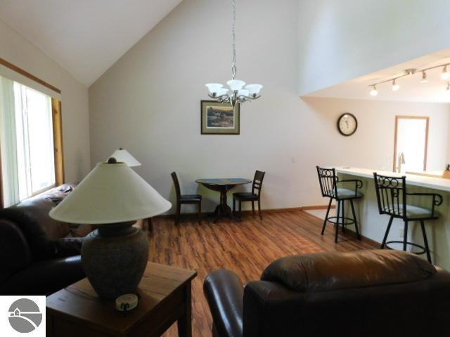 12149 Cabin Ln, Rapid City, MI 49676 - living area with a chandelier, healthy amount of natural light, wood finished floors, and high vaulted ceiling