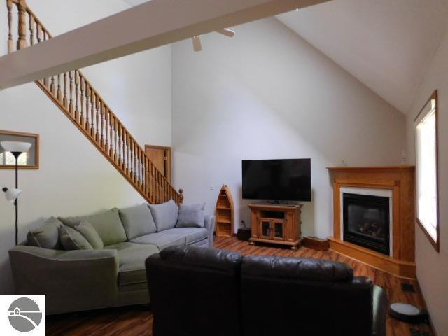12149 Cabin Ln, Rapid City, MI 49676 - living area featuring dark wood-style floors, stairway, high vaulted ceiling, and a glass covered fireplace