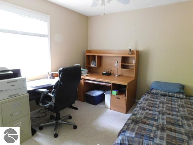 12149 Cabin Ln, Rapid City, MI 49676 - bedroom featuring light colored carpet, a desk, and ceiling fan