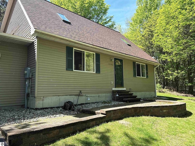 12149 Cabin Ln, Rapid City, MI 49676 - view of front of home with entry steps, a shingled roof, and a front lawn