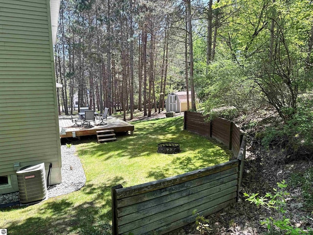 12149 Cabin Ln, Rapid City, MI 49676 - view of green lawn featuring a wooden deck, a fire pit, and cooling unit