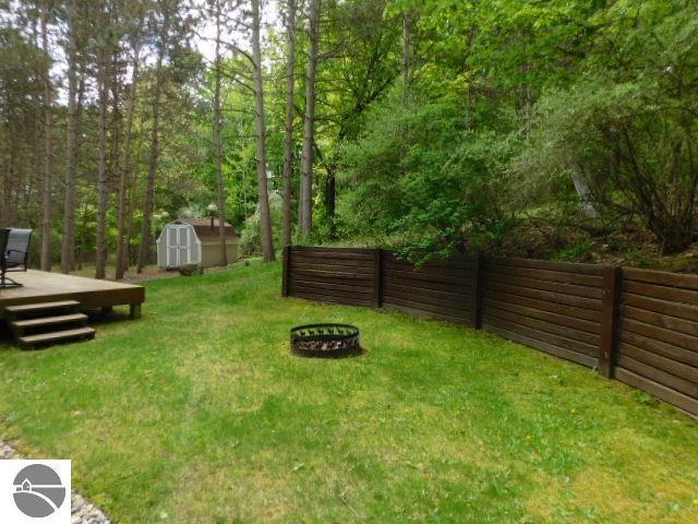 12149 Cabin Ln, Rapid City, MI 49676 - view of yard with an outdoor fire pit and a wooden deck
