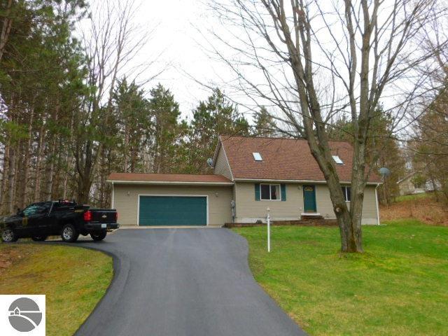 12149 Cabin Ln, Rapid City, MI 49676 - single story home with a garage, driveway, and a front lawn