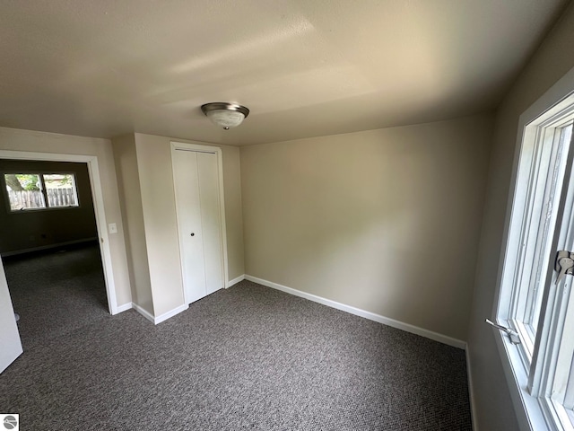 1007 Park St, Mount Pleasant, MI 48858 - unfurnished bedroom with dark carpet, baseboards, and a closet