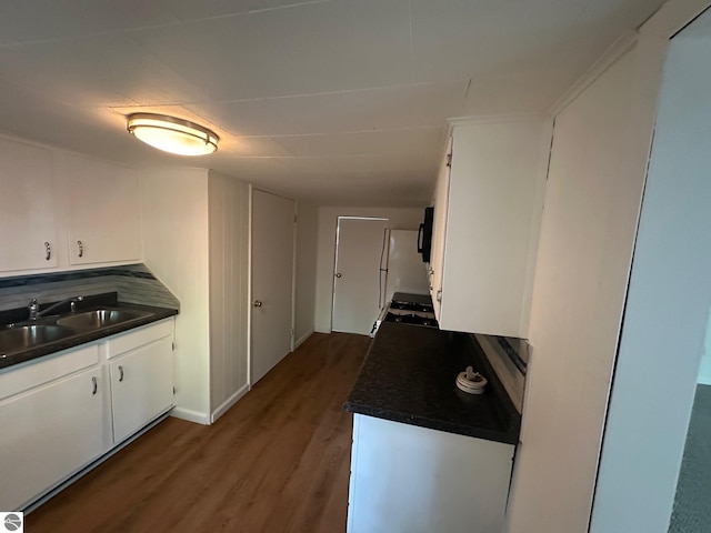 1007 Park St, Mount Pleasant, MI 48858 - kitchen featuring dark countertops, a sink, wood finished floors, white cabinetry, and black microwave