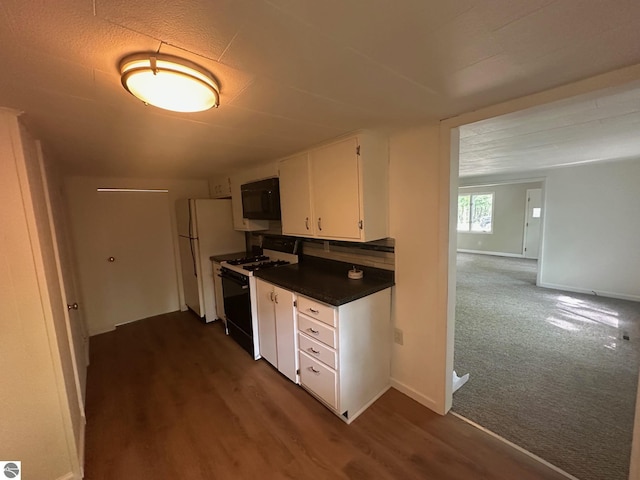 1007 Park St, Mount Pleasant, MI 48858 - kitchen featuring gas range, black microwave, freestanding refrigerator, white cabinetry, and dark countertops