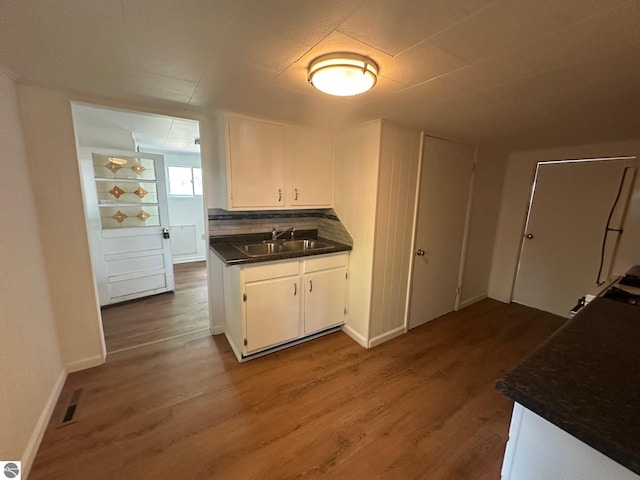 1007 Park St, Mount Pleasant, MI 48858 - kitchen featuring a sink, dark countertops, wood finished floors, and white cabinetry