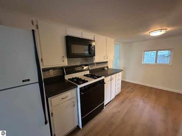 1007 Park St, Mount Pleasant, MI 48858 - kitchen with black microwave, range with gas stovetop, freestanding refrigerator, and dark countertops