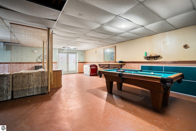 11567 Lake Valley Rd, Kalkaska, MI 49646 - playroom with concrete flooring, a paneled ceiling, pool table, wainscoting, and french doors