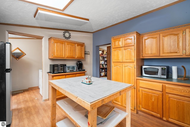 11567 Lake Valley Rd, Kalkaska, MI 49646 - kitchen with stainless steel appliances, a textured ceiling, light wood-style flooring, crown molding, and brown cabinetry