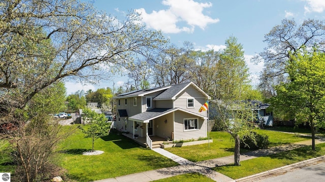 855 E State St, Traverse City, MI 49686 - view of front of property featuring a front lawn, covered porch, roof mounted solar panels, and roof with shingles