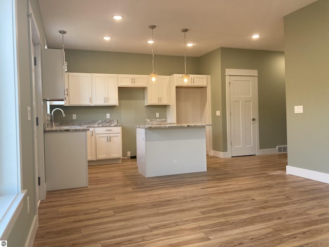 9296 S Flaska Dr Unit 14, Cedar, MI 49621 - kitchen featuring a center island, baseboards, light wood-style flooring, white cabinets, and recessed lighting