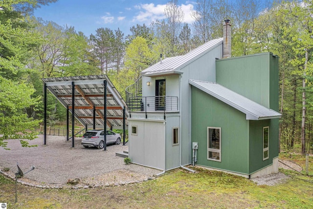145 Fisher Rd, Traverse City, MI 49685 - view of home's exterior with a chimney, metal roof, a balcony, a standing seam roof, and a detached carport