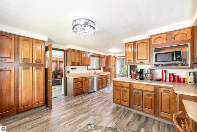 6770 N Crystal, Vestaburg, MI 48891 - kitchen with appliances with stainless steel finishes, brown cabinetry, a textured ceiling, light countertops, and light wood finished floors