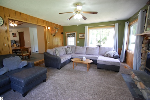 1137 Stoney Ridge Rd, West Branch, MI 48661 - carpeted living room featuring ceiling fan, wood walls, and a stone fireplace