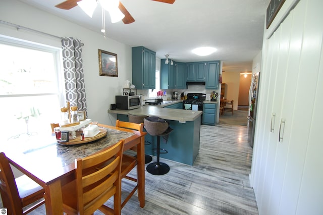 1137 Stoney Ridge Rd, West Branch, MI 48661 - kitchen featuring blue cabinets, appliances with stainless steel finishes, a ceiling fan, a peninsula, and light wood-style floors