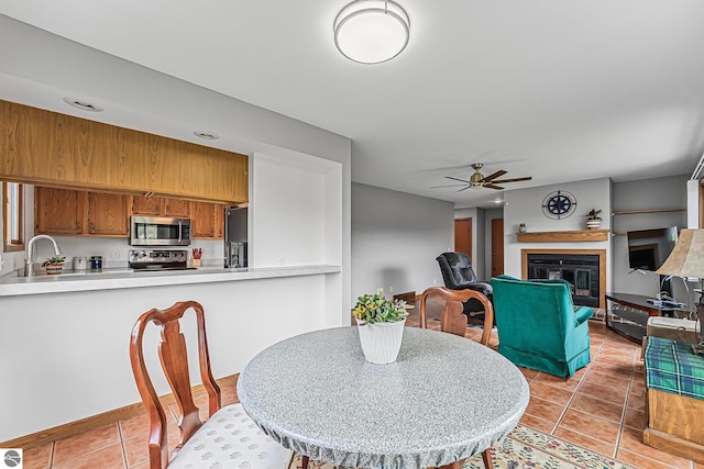 2683 Green Meadows Dr Unit 10, Traverse City, MI 49685 - dining area with a ceiling fan, light tile patterned flooring, and a glass covered fireplace