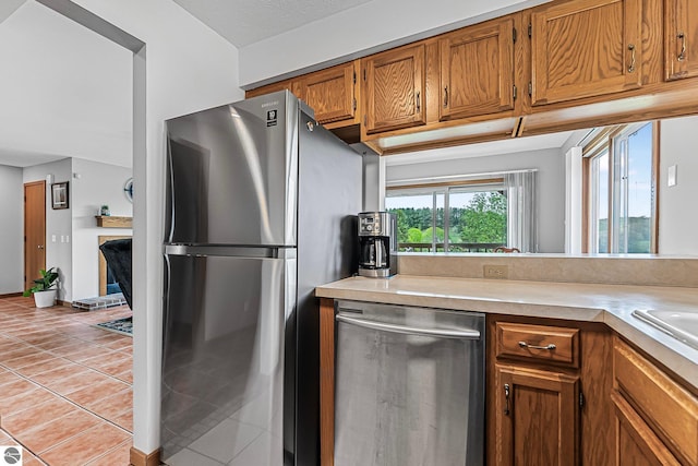 2683 Green Meadows Dr Unit 10, Traverse City, MI 49685 - kitchen with appliances with stainless steel finishes, brown cabinets, light tile patterned flooring, and light countertops
