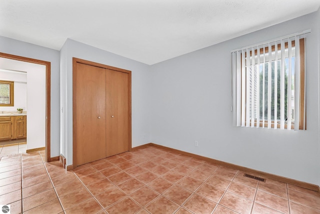 2683 Green Meadows Dr Unit 10, Traverse City, MI 49685 - unfurnished bedroom with a closet, light tile patterned floors, and baseboards