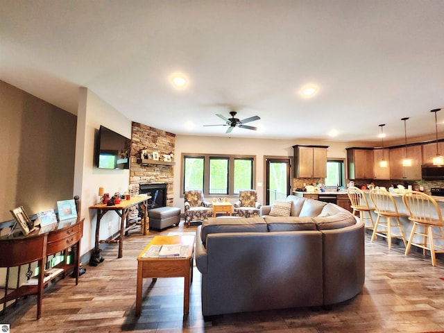 6238 E Gallivan Rd, Cedar, MI 49621 - living area with wood finished floors, healthy amount of natural light, a ceiling fan, a stone fireplace, and recessed lighting