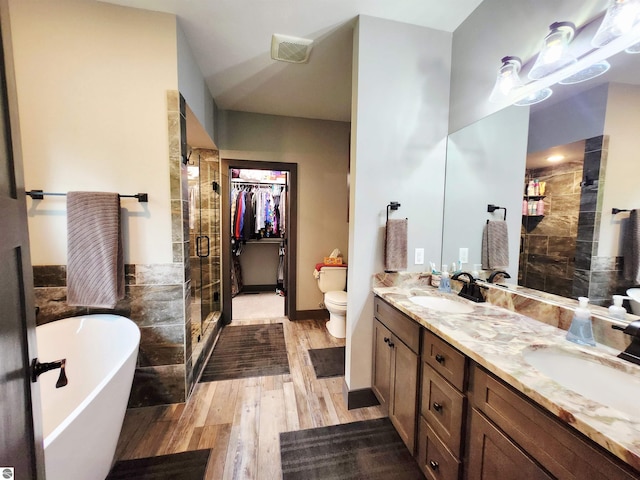 6238 E Gallivan Rd, Cedar, MI 49621 - bathroom with double vanity, a shower stall, a freestanding bath, wood finished floors, and toilet