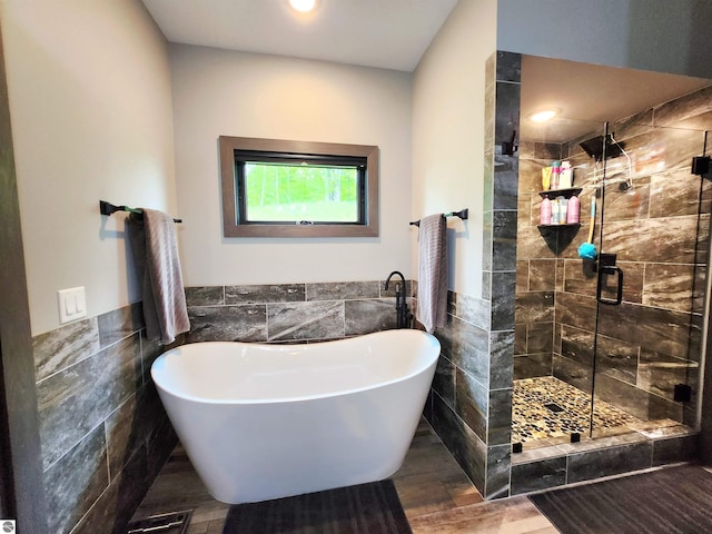 6238 E Gallivan Rd, Cedar, MI 49621 - full bathroom with tile walls, a soaking tub, a stall shower, wainscoting, and wood finished floors