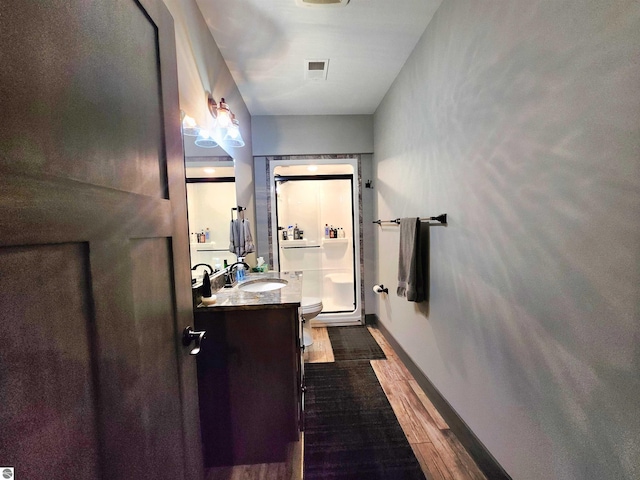 6238 E Gallivan Rd, Cedar, MI 49621 - bathroom featuring vanity, wood finished floors, toilet, a shower, and baseboards