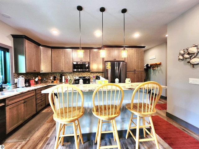 6238 E Gallivan Rd, Cedar, MI 49621 - kitchen with appliances with stainless steel finishes, dark wood finished floors, tasteful backsplash, a breakfast bar, and a center island