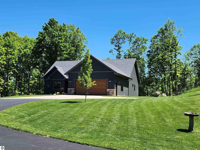 6238 E Gallivan Rd, Cedar, MI 49621 - view of front of property featuring stone siding, concrete driveway, a garage, a front yard, and board and batten siding