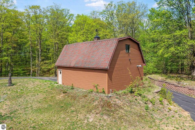 2460 E 26th Rd, Cadillac, MI 49601 - view of side of property with a gambrel roof, a view of trees, a yard, and an outbuilding