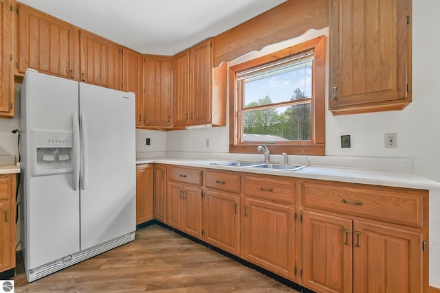 2460 E 26th Rd, Cadillac, MI 49601 - kitchen featuring white fridge with ice dispenser, a sink, light countertops, light wood-style floors, and brown cabinets