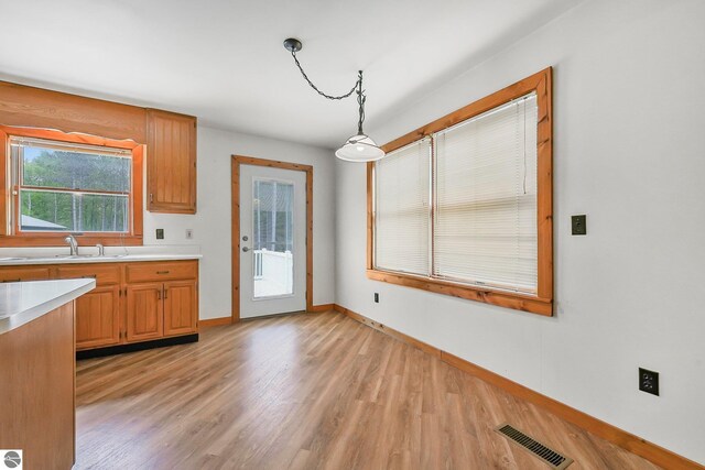 2460 E 26th Rd, Cadillac, MI 49601 - kitchen featuring light countertops, light wood finished floors, baseboards, hanging light fixtures, and a sink