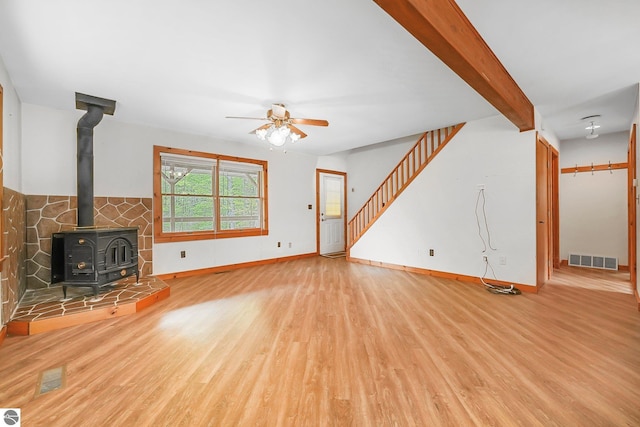 2460 E 26th Rd, Cadillac, MI 49601 - unfurnished living room with wood finished floors, a ceiling fan, a wood stove, and baseboards