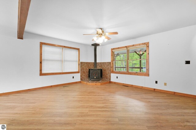 2460 E 26th Rd, Cadillac, MI 49601 - unfurnished living room with wood finished floors, a wood stove, baseboards, and ceiling fan