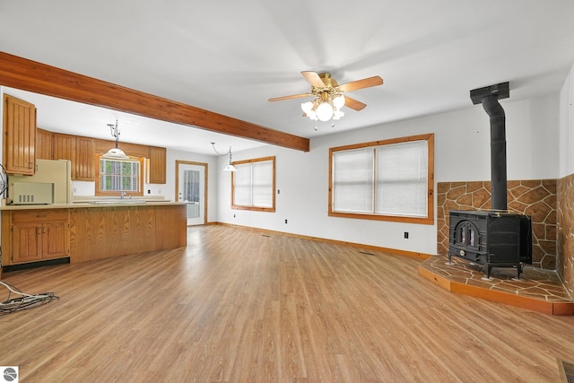 2460 E 26th Rd, Cadillac, MI 49601 - unfurnished living room featuring a wood stove, light wood-type flooring, baseboards, ceiling fan, and beam ceiling