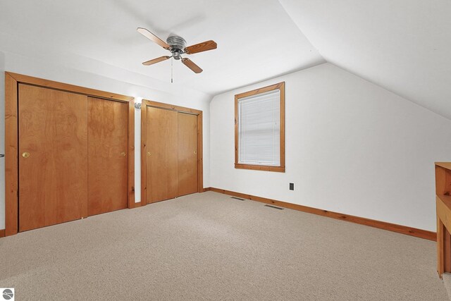 2460 E 26th Rd, Cadillac, MI 49601 - unfurnished bedroom featuring multiple closets, carpet, vaulted ceiling, baseboards, and a ceiling fan