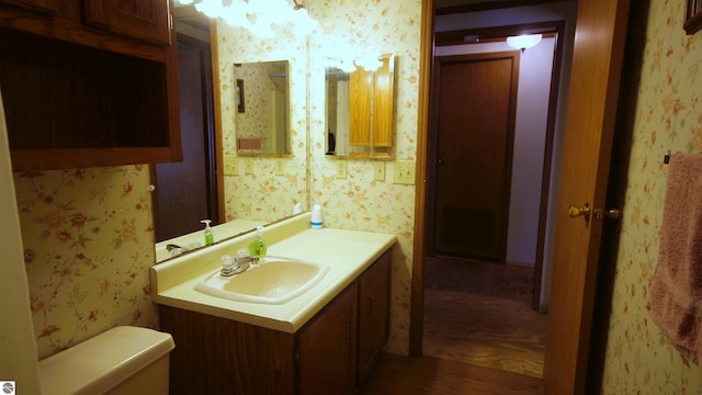 120 Lorna Ln, Roscommon, MI 48653 - bathroom featuring wallpapered walls, wood finished floors, vanity, and toilet