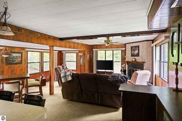 1912 Rosenburg Rd, Kalkaska, MI 49646 - carpeted living room with wood walls, ceiling fan, and a fireplace