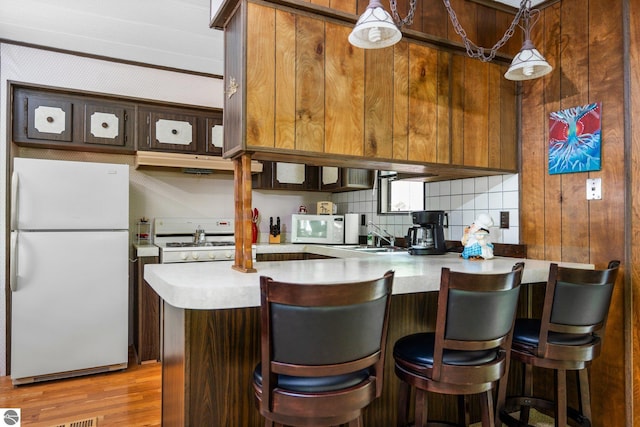 1912 Rosenburg Rd, Kalkaska, MI 49646 - kitchen with white appliances, under cabinet range hood, light countertops, a peninsula, and tasteful backsplash