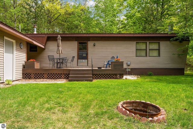 1912 Rosenburg Rd, Kalkaska, MI 49646 - back of property with a fire pit, a wooden deck, and a yard