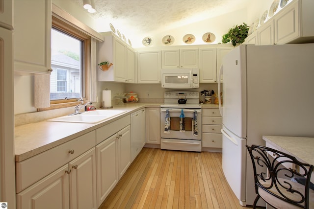 1162 Hemingway Ln, Traverse City, MI 49686 - kitchen featuring white appliances, a sink, light countertops, light wood-style flooring, and lofted ceiling