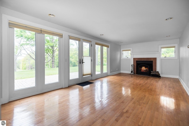6675 Walker St, Benzonia, MI 49616 - unfurnished living room featuring light wood-style floors, a brick fireplace, and baseboards