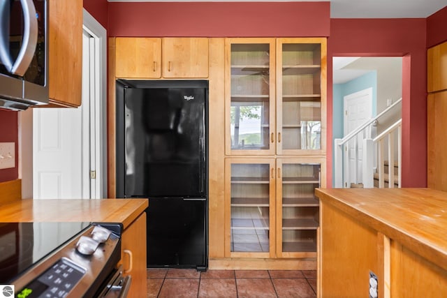 6675 Walker St, Benzonia, MI 49616 - kitchen with butcher block countertops, stainless steel microwave, freestanding refrigerator, stove, and tile patterned floors