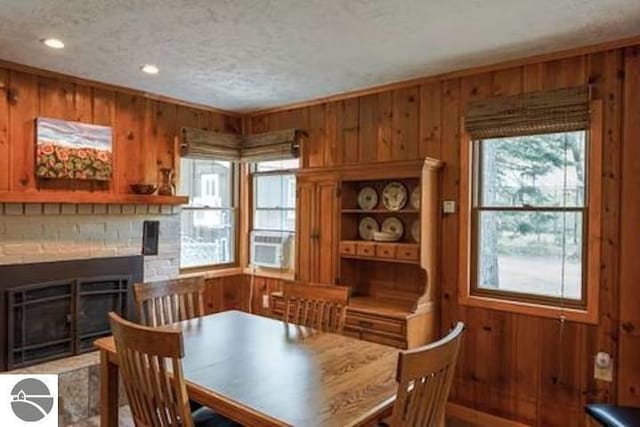 2401 J Maddy Pkwy, Interlochen, MI 49643 - dining room with wooden walls, a textured ceiling, a fireplace, and recessed lighting