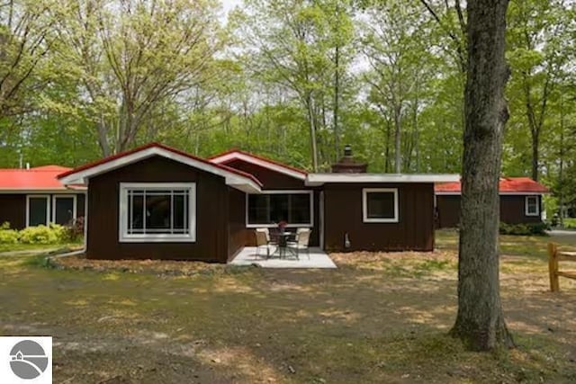 2401 J Maddy Pkwy, Interlochen, MI 49643 - rear view of property with a patio, a chimney, and view of wooded area