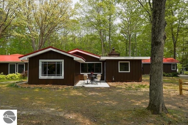 2401 J Maddy Pkwy, Interlochen, MI 49643 - rear view of property with board and batten siding, a chimney, and a patio