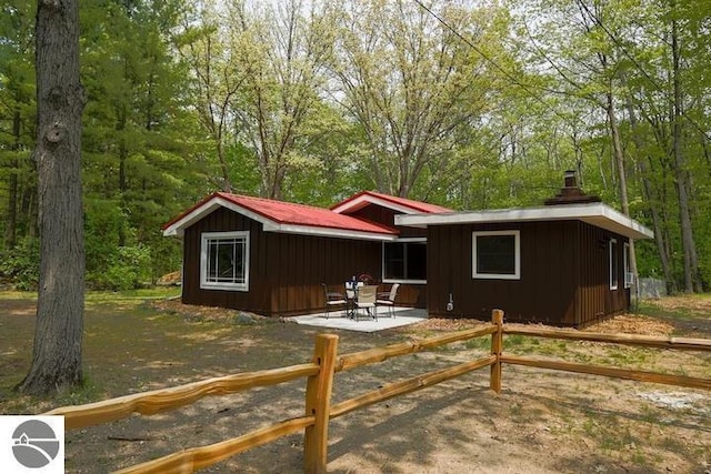 2401 J Maddy Pkwy, Interlochen, MI 49643 - view of front facade featuring board and batten siding, a patio area, and a chimney