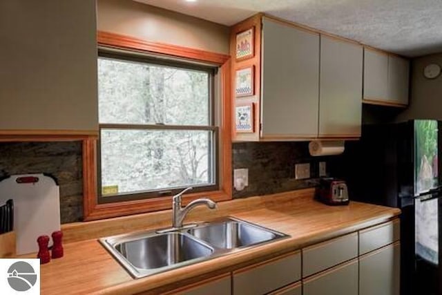 2401 J Maddy Pkwy, Interlochen, MI 49643 - kitchen with a sink, light countertops, plenty of natural light, freestanding refrigerator, and a textured ceiling