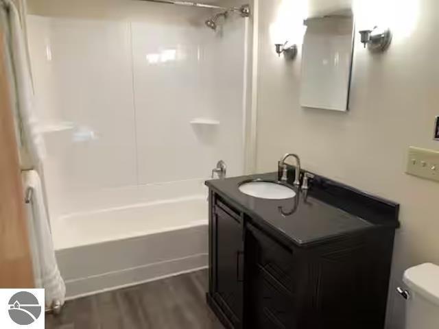 2401 J Maddy Pkwy, Interlochen, MI 49643 - bathroom featuring washtub / shower combination, vanity, toilet, and wood finished floors